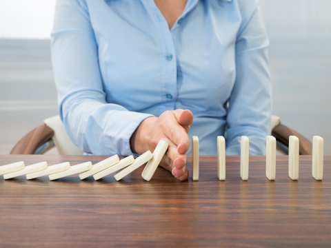 Photo of lady stopping dominoes from falling